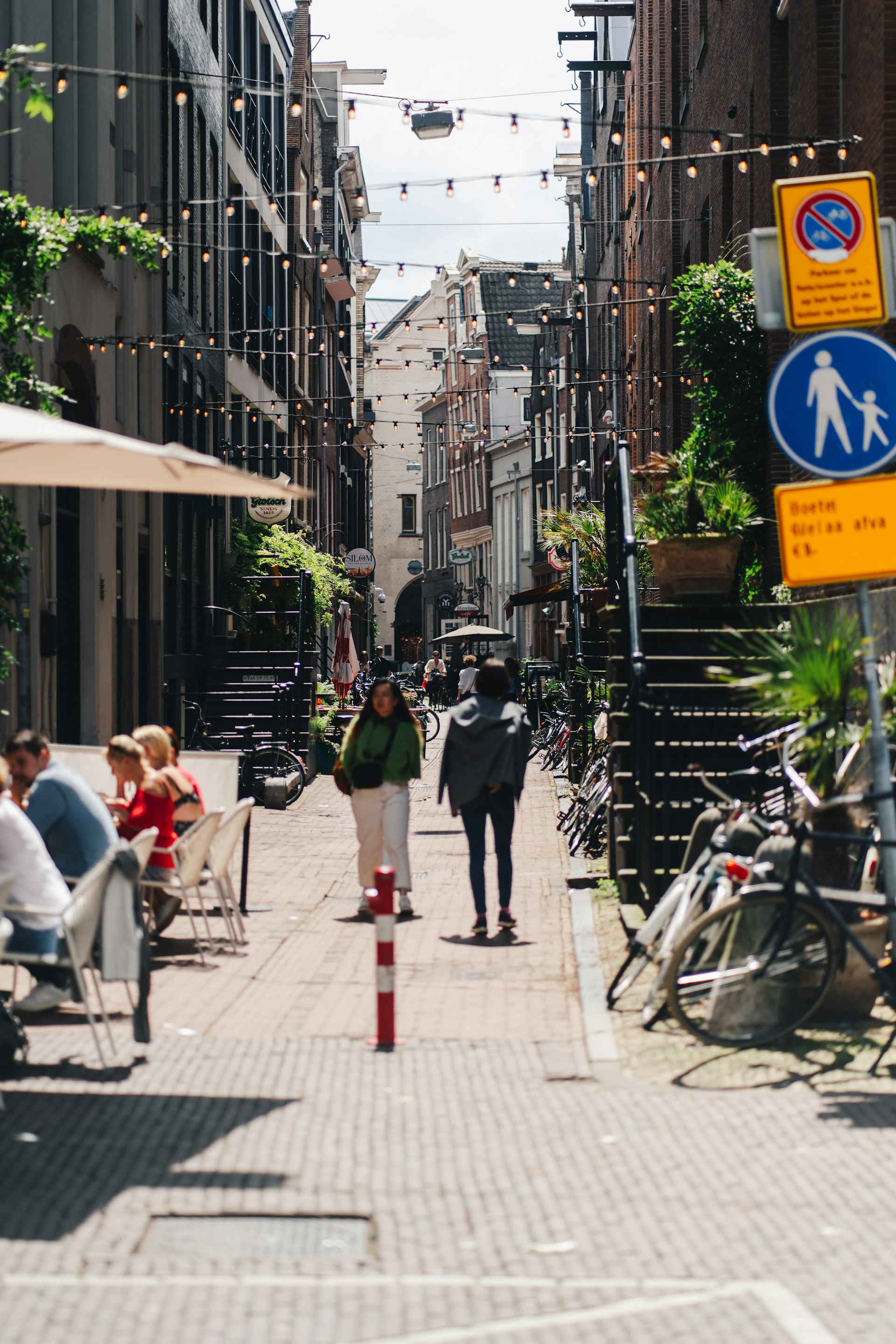 Het beeld lijkt zwaar vervormd met digitale haperingen, waardoor het moeilijk is om de scène duidelijk te identificeren. Sommige vormen suggereren mensen die langs een stadsstraat lopen met gebouwen en bewegwijzering op de achtergrond.