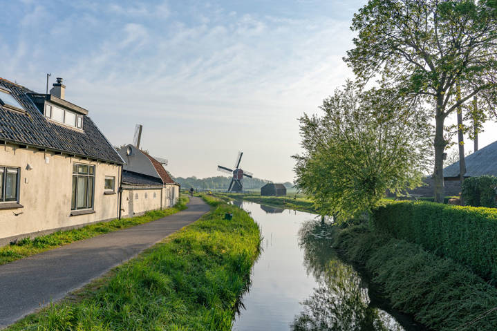 Prachtig Shot Van Een Waterkanaal Langs Een Smal Weggetje Met Een Windmolen Op Een Veld1200